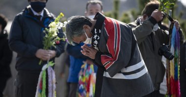 A man prays in front of the sea in Hisanohama, Fukushima prefecture on the 10th anniversary of the 9.0 magnitude earthquake which triggered a tsunami and nuclear disaster, Japan, March 11, 2021. (AFP)