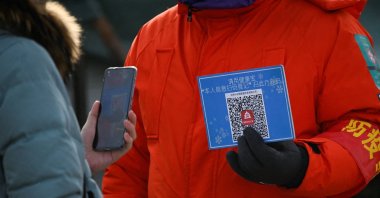 A woman using her mobile phone to scan a QR code for health registration before entering an outdoor ice rink in Beijing, China, Jan 12, 2021. (AFP Photo)