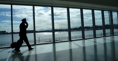 A pilot walks past the windows at LaGuardia Airport in New York, the U.S., March 6, 2021. (AFP Photo)