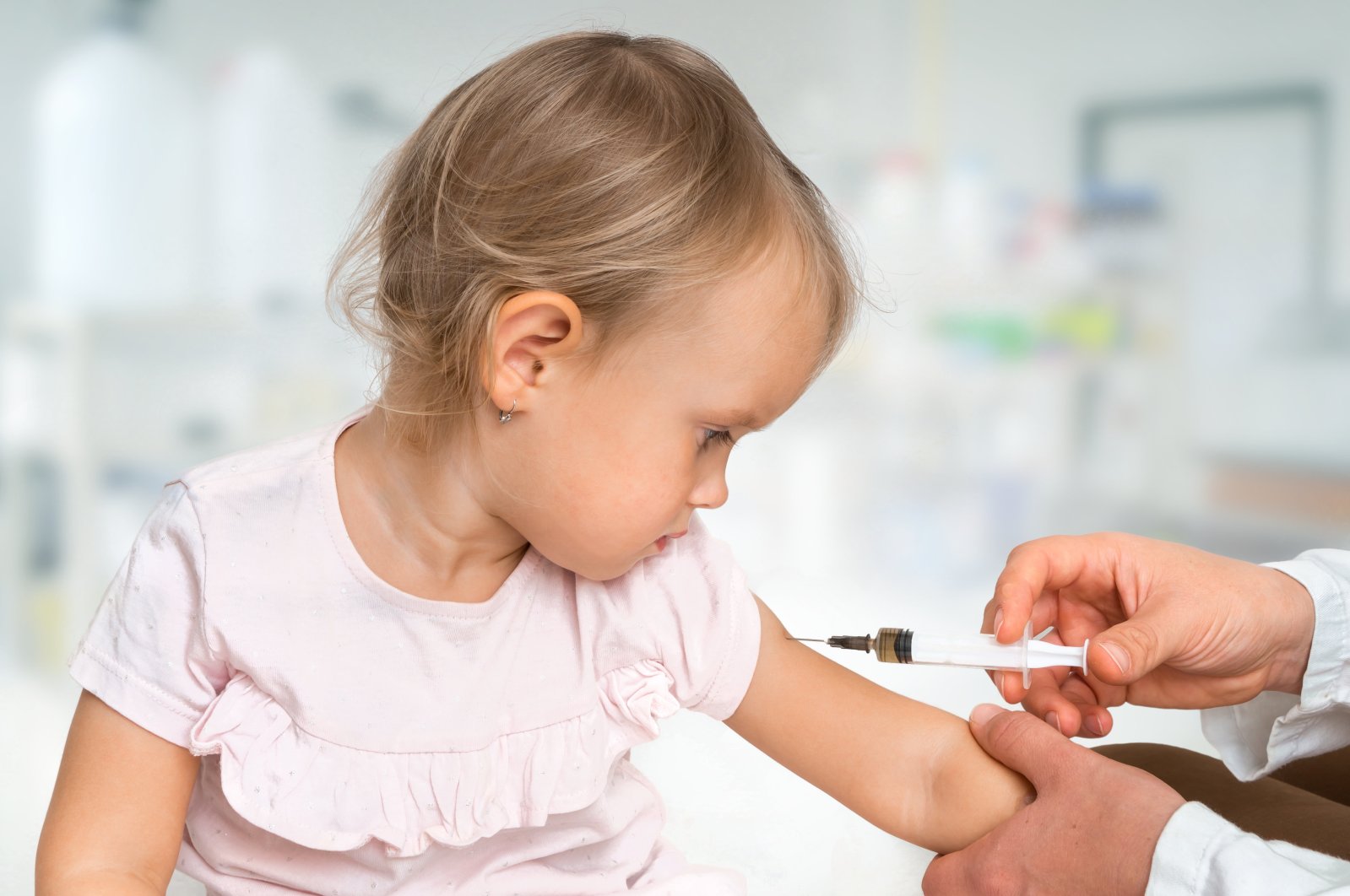 A pediatric doctor injects a dose of a vaccine into a child's shoulder. (Getty Images)