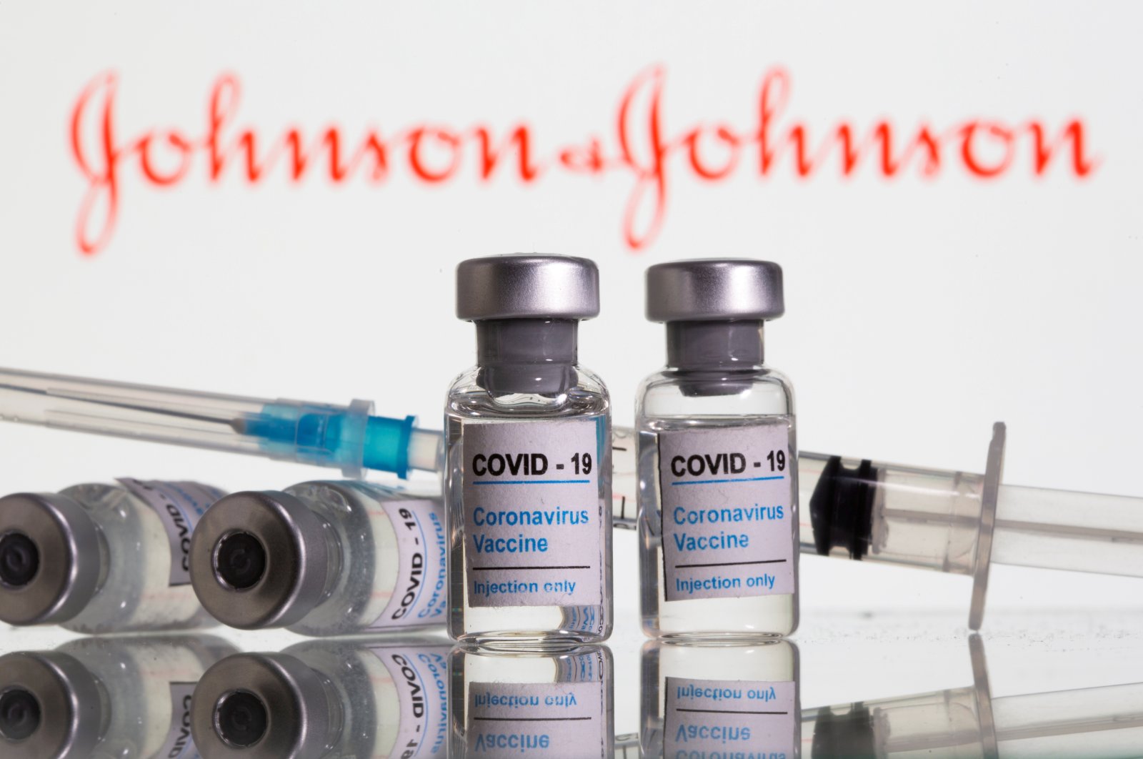 Vials labeled "COVID-19 Coronavirus Vaccine" and a syringe are seen in front of the displayed Johnson&Johnson logo. Feb. 9, 2021. (Reuters Photo)