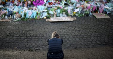 A mourner sits in front of a memorial site at the Clapham Common Bandstand, following the kidnap and murder of Sarah Everard, in London, Britain, March 14, 2021. (Reuters Photo)