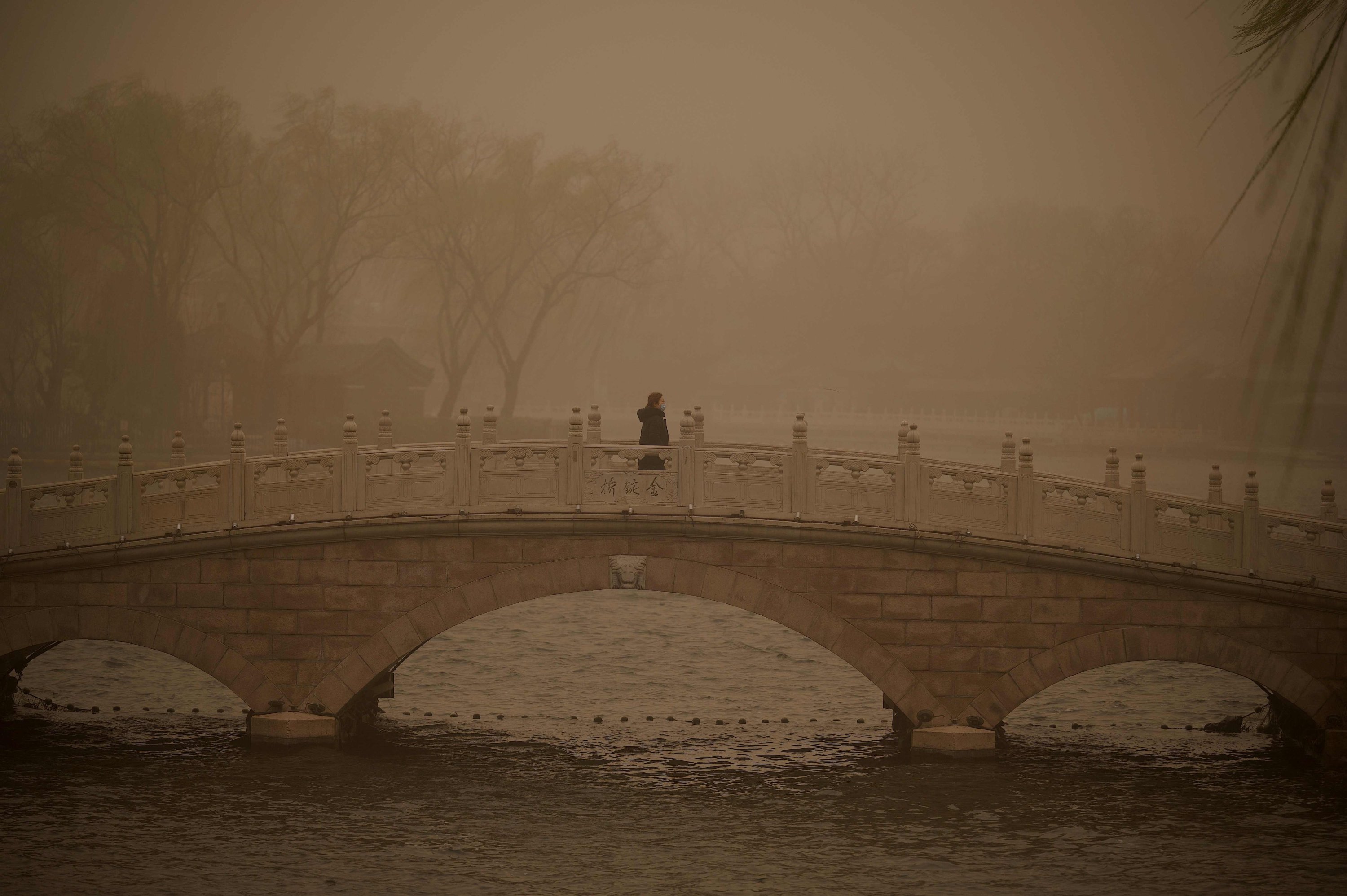 A woman crosses a bridge at Huahai lake during a sandstorm in Beijing, China, March 15, 2021. (AFP Photo)