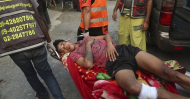 An injured man lies on a stretcher being carried by members of a volunteer rescue team in Mandalay, Myanmar Sunday, March 14, 2021. (AP Photo)
