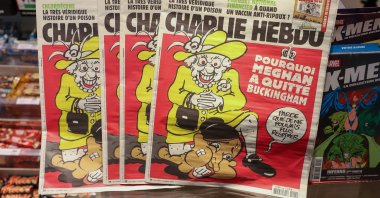 French satirical weekly Charlie Hebdo's edition displays a cover with a satirical drawing representing Queen Elizabeth kneeling on Duchess of Sussex Meghan's neck, echoing George Floyd’s killing, Paris, France, March 15, 2021. (Getty Images)