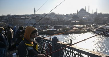 Men fish from the Galata bridge, in Istanbul, Turkey, Mar. 9, 2021. (AFP PHOTO) 