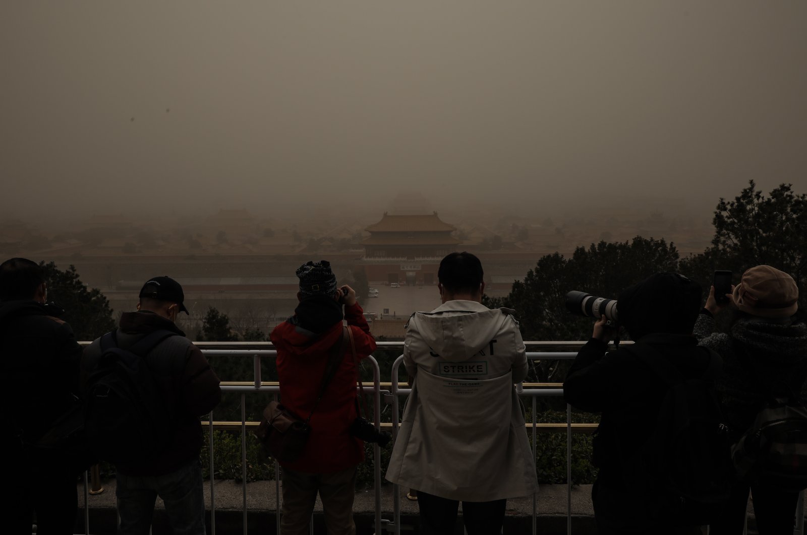 People take photos of the Forbidden City, as seen from a viewing deck of Jingshan Park, amid a sandstorm, in Beijing, China, March 15, 2021. (EPA Photo)