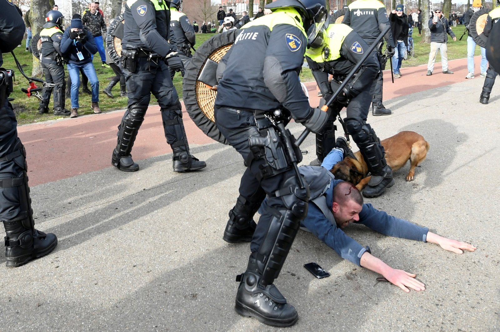 A demonstrator is bitten by a police dog while fighting with police during a protest against the coronavirus disease (COVID-19) restrictions in The Hague, Netherlands, March 14, 2021. (Reuters Photo)