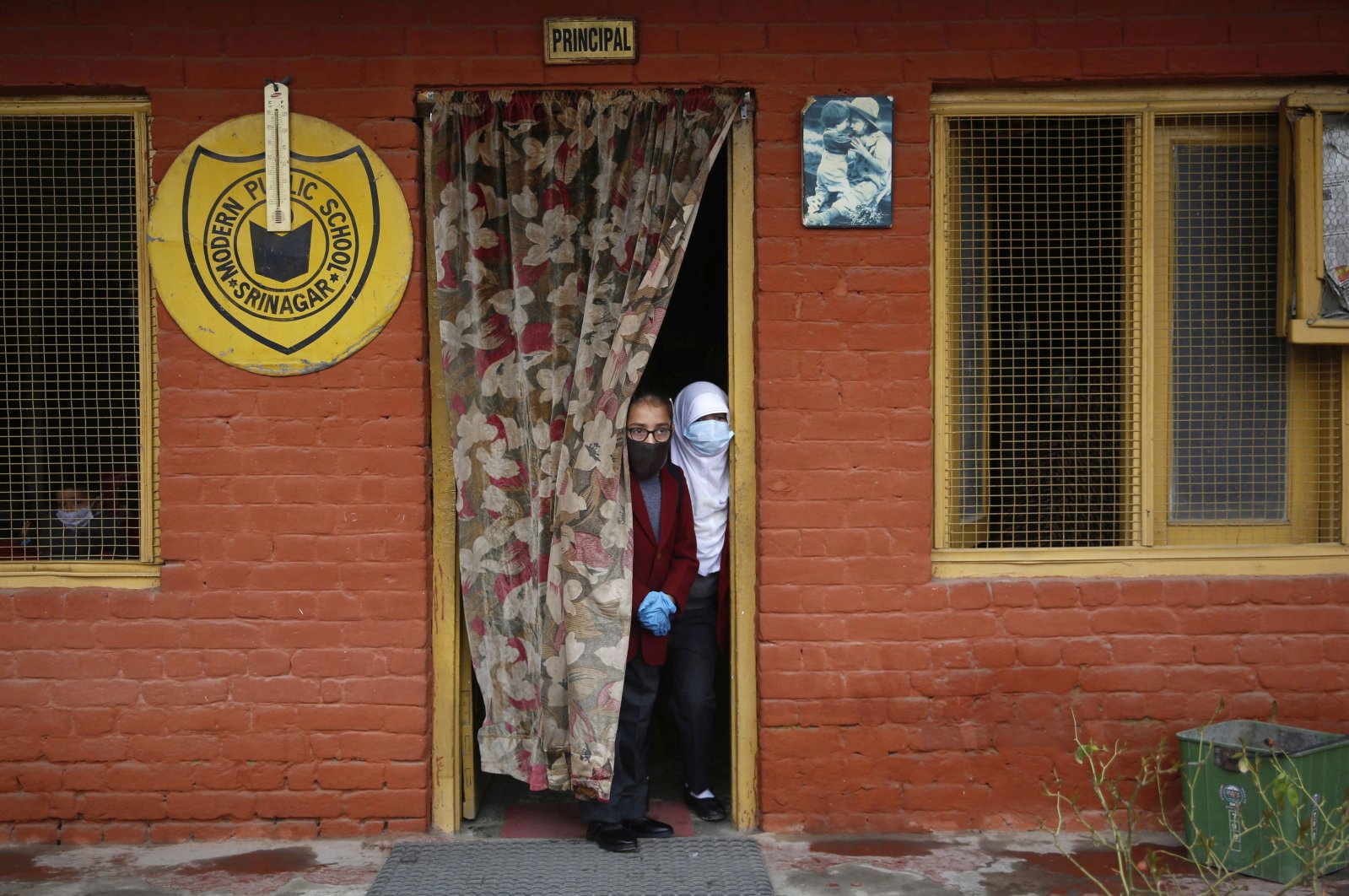 Students peer through a door as they attend school, in Srinagar, Indian Kashmir, March 15, 2021. (EPA)