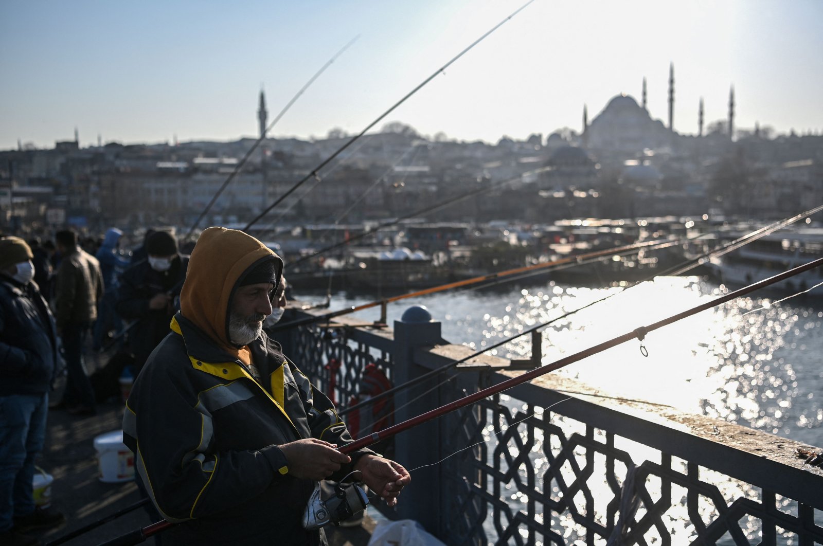 Men fish from the Galata bridge, in Istanbul, Turkey, Mar. 9, 2021. (AFP PHOTO) 