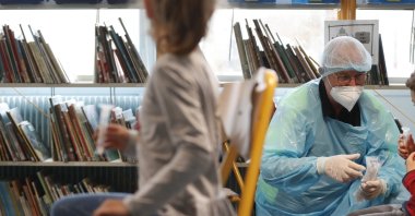 A medical worker waits as children undergo saliva COVID-19 tests at the Niederau school in Strasbourg, eastern France, March 11, 2021. (AP Photo)