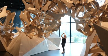 A visitor photographs a wooden sculpture made of over 6,000 parts and meant to depict the complexity of nature during a press preview at the new Futurium museum in the city center in Berlin, Germany, Aug. 27, 2019. (Getty Images)