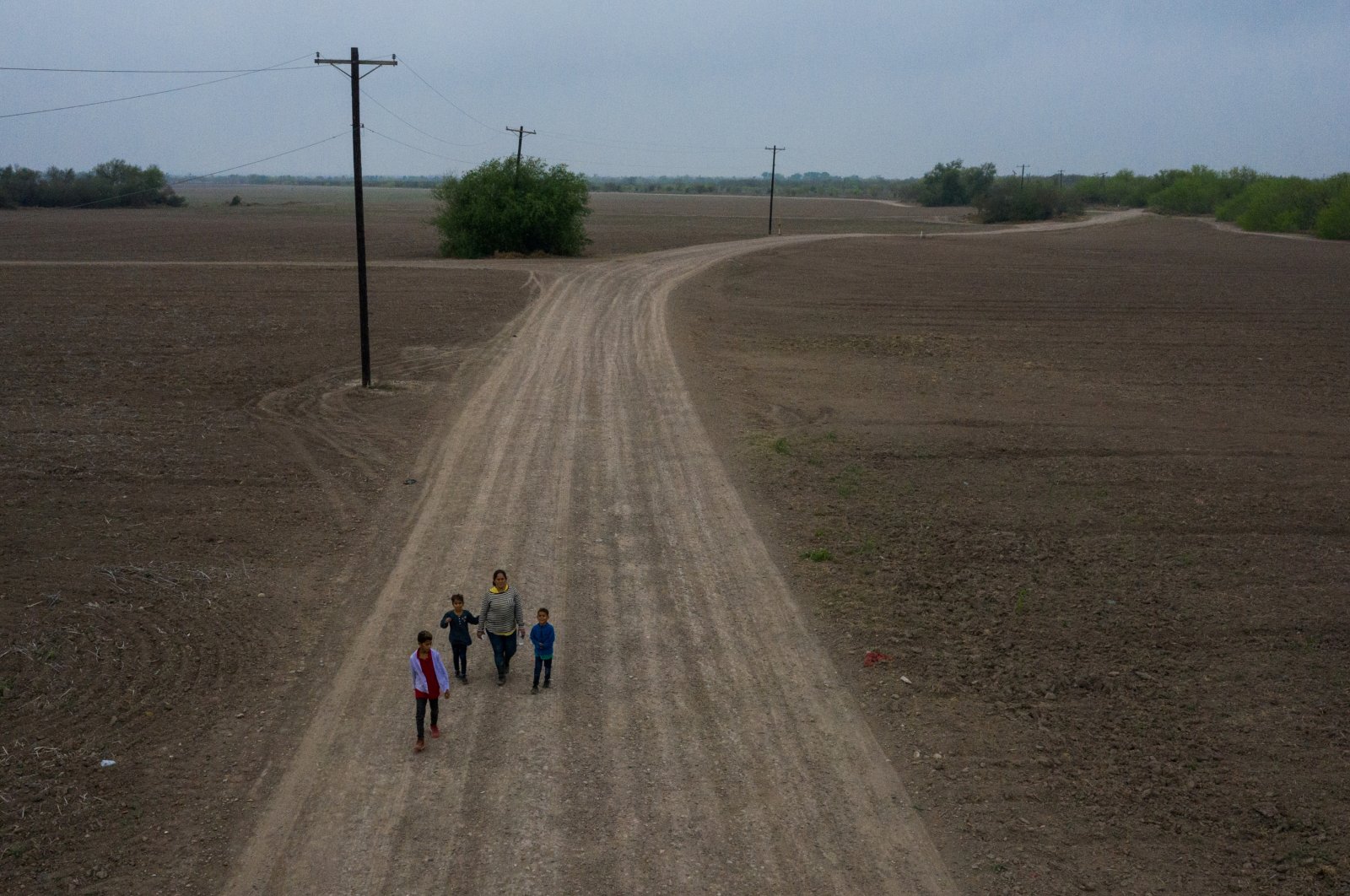 Sonia, an asylum-seeking migrant from Honduras, walks down a dirt road with her three children Jefferson, 9, Scarlet, 7, and David, 6, after they crossed the Rio Grande river into the United States from Mexico on a raft in Penitas, Texas, U.S., March 16, 2021. (Reuters Photo) 