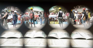 Demonstrators are seen from the holes of a shield during a protest against the military coup in Yangon, Myanmar, March, 18, 2021. (EPA)