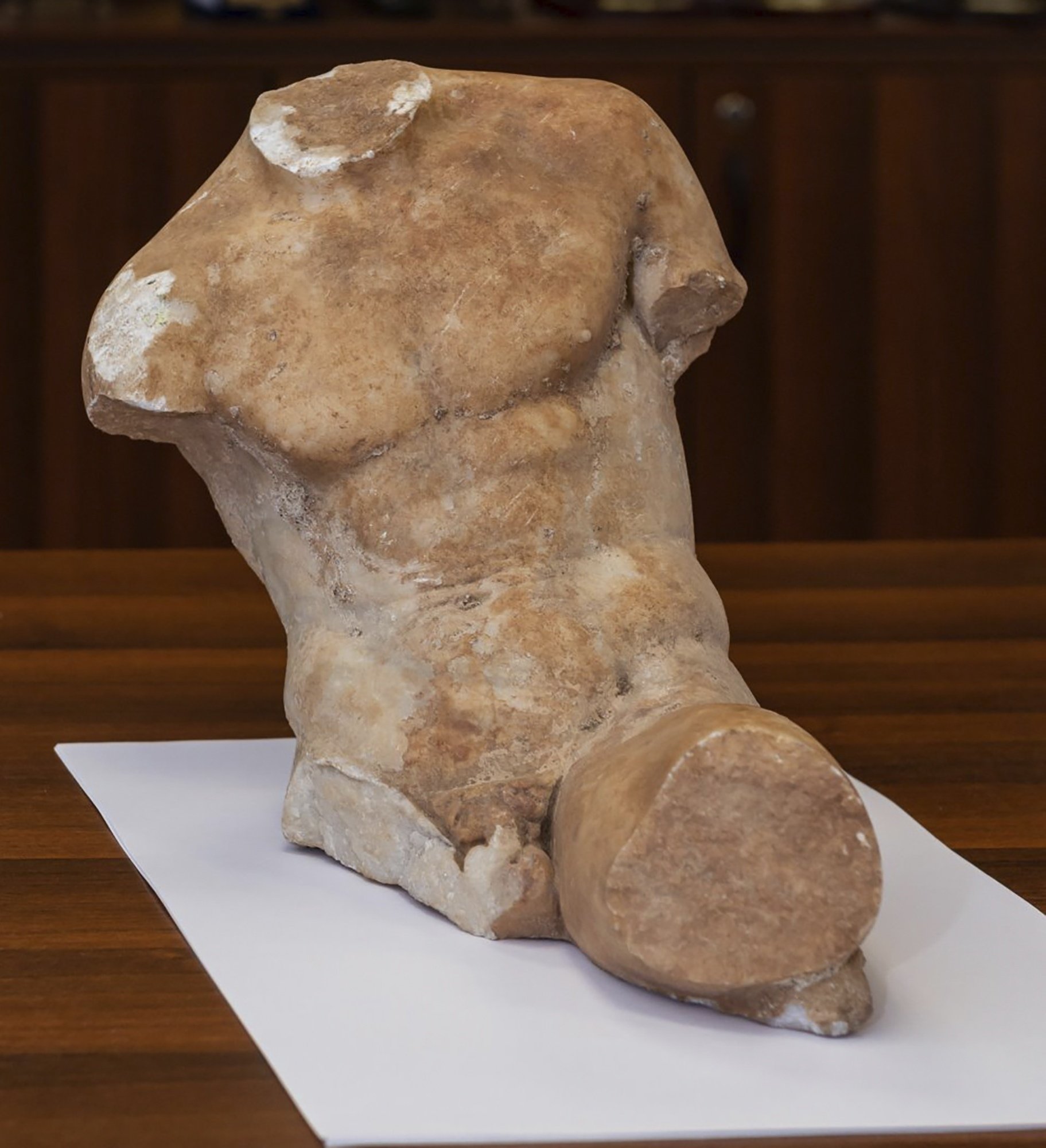 A 5th century B.C. statue about 37 centimeters (14.5 inches), depicting a seated young man who slightly reclines, can be seen, Athens, Greece, March 19, 2021. (Greek Police via AP)