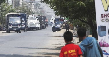 People watch as a row of vehicles by security forces are parked on a road in Mandalay, Myanmar, March 19, 2021. (AP Photos)