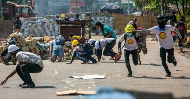 Protesters run during a crackdown by security forces on a demonstration against the military coup in Yangon's Thaketa township on March 19, 2021. (AFP Photo)