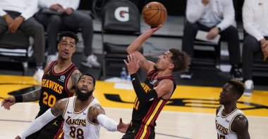 Atlanta Hawks guard Trae Young (C) shoots over Los Angeles Lakers forward Markieff Morris (L) and Dennis Schroder (R) during an NBA game, Los Angeles, U.S., March 20, 2021. (AP Photo)
