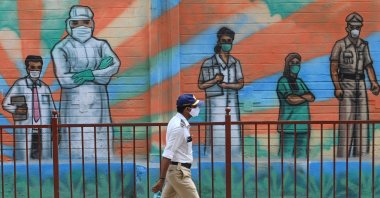 A police officer walks past a mural depicting frontline COVID-19 warriors, in Mumbai, India, on March 21, 2021. (AFP Photo)