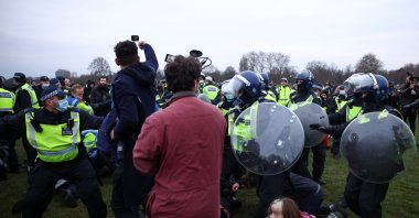 Members of the media stand next to police officers detaining people during a protest against the lockdown, amid the spread of the coronavirus disease, in London, Britain, March 20, 2021. (Reuters Photo)