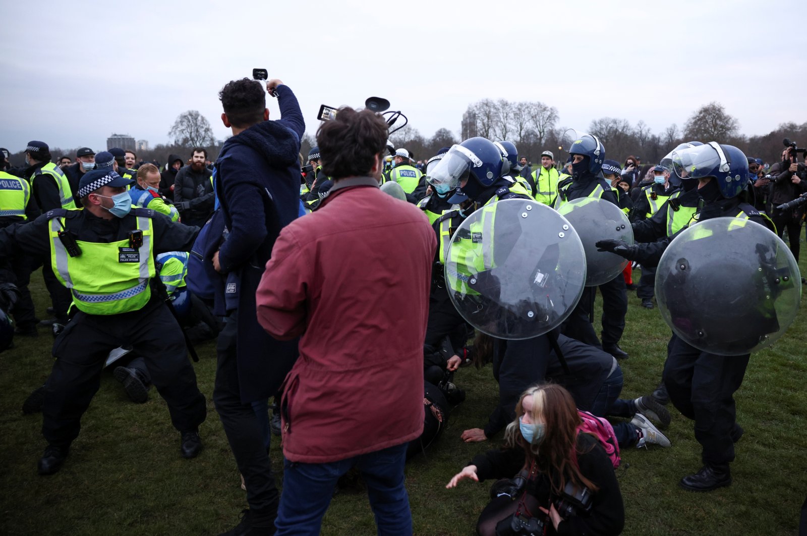 Members of the media stand next to police officers detaining people during a protest against the lockdown, amid the spread of the coronavirus disease, in London, Britain, March 20, 2021. (Reuters Photo)
