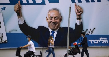 People pass an election campaign billboard for the Likud party that shows a portrait of its leader Prime Minister Benjamin Netanyahu, in Ramat Gan, Israel, March 21, 2021. (AP)