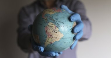 
A man wearing medical gloves holds a globe in his hands, Buenos Aires, Argentina, Aug. 6, 2020. (Getty Images)