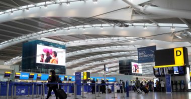 Travelers wearing face coverings walk with their luggage in the almost deserted departures hall at Terminal 5 of Heathrow Airport in west London, U.K., Dec. 21, 2020. (AFP Photo)