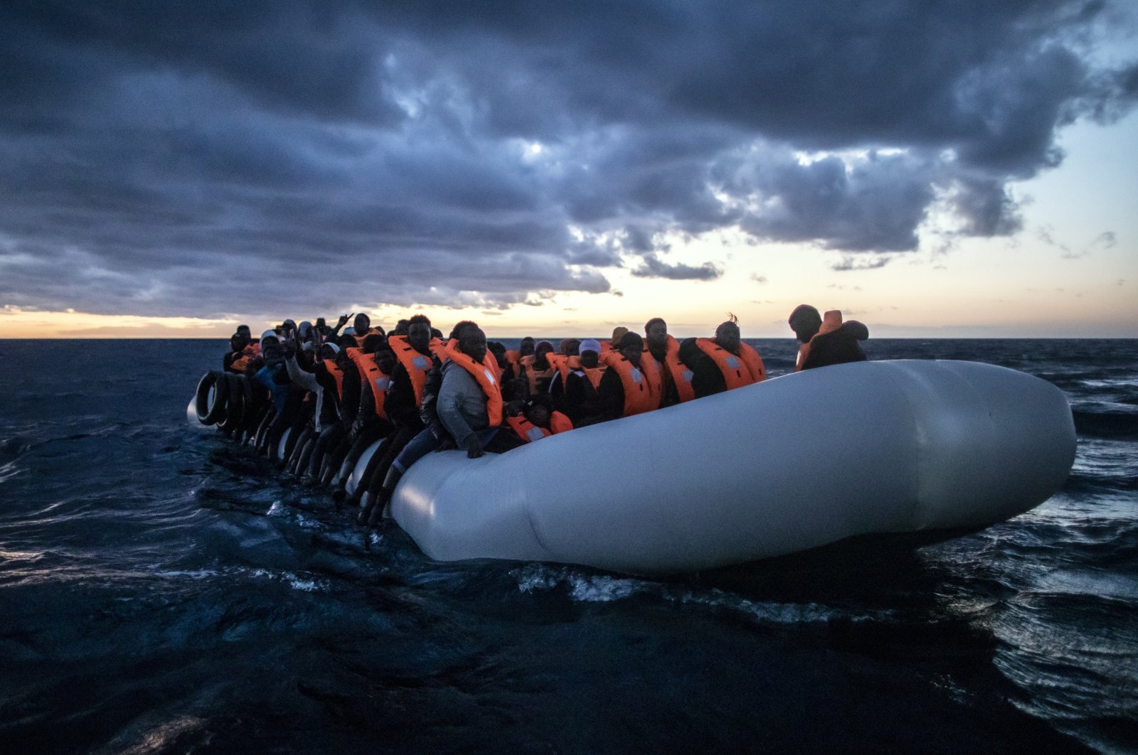 Migrants and refugees from various African nationalities wait on a rubber boat as aid workers on a rescue vessel of the Spanish NGO Open Arms approach in international waters in the Mediterranean Sea, 80 miles off the Libyan coast, Feb. 13, 2021. (AP Photo)
