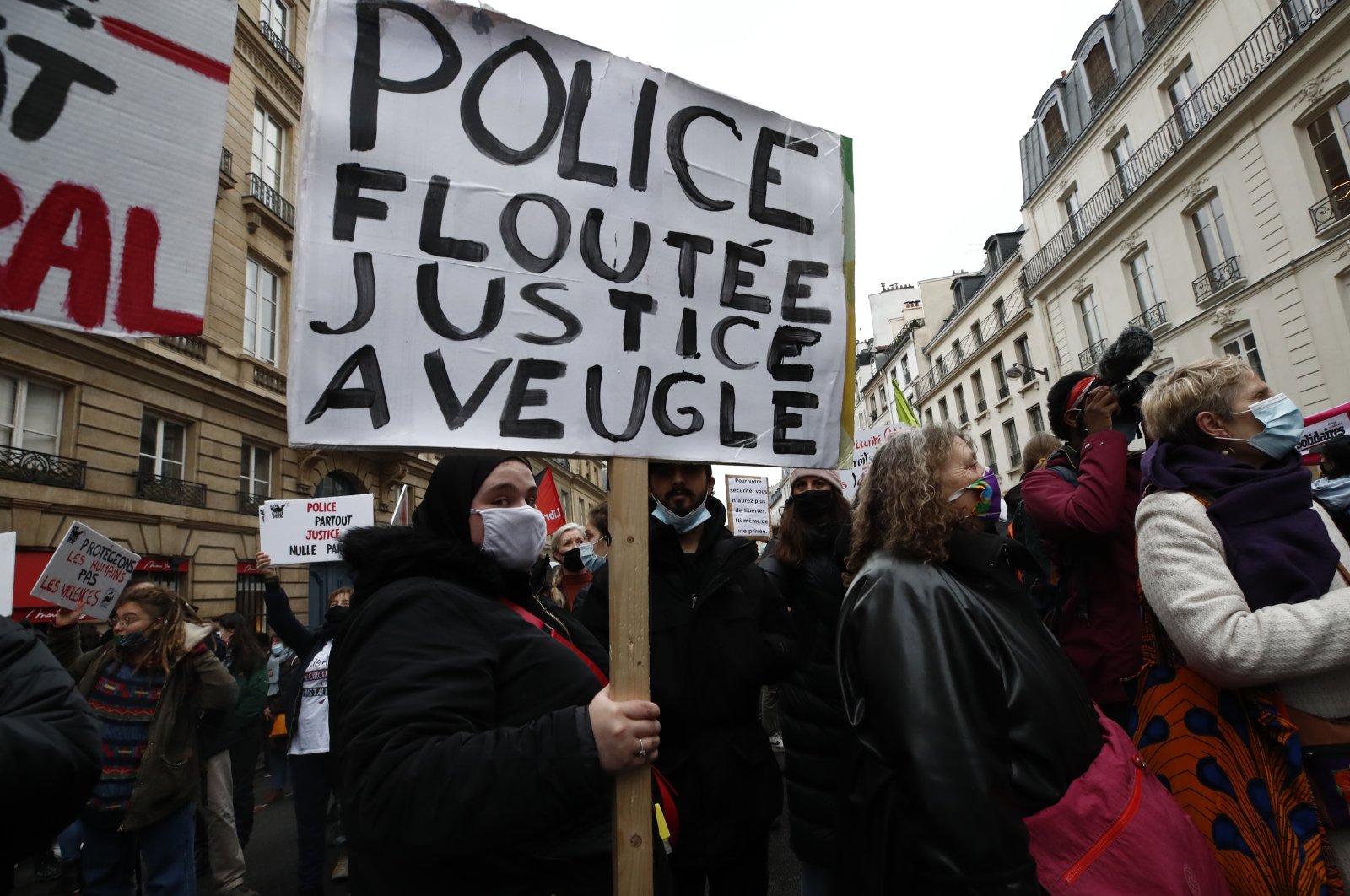 A woman holds a poster reading "Blurred police, blind justice" during a demonstration, March 16, 2021 in Paris, France. (AP Photo)