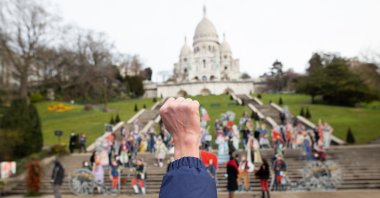 A man raises his fist during the celebration of the 150 year anniversary of La Commune de Paris at the Louise Michel Square next to the Basilica Sacre Coeur, in Paris, France, March 18, 2020. (Photo by Raphael Lafargue/abacapress.com via Reuters)