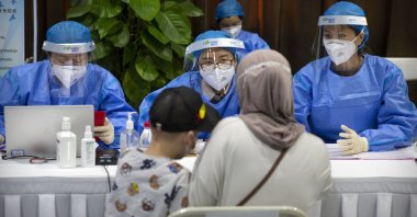 Workers wearing protective gear register a person during a COVID-19 vaccination session for resident foreign journalists at a vaccination center in Beijing, Tuesday, March 23, 2021. (AP Photo)