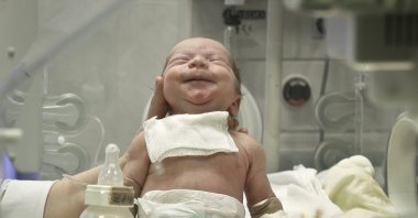 A newborn baby appears to smile after having a meal at the intensive care unit of the Marie Curie children's hospital, on March 18, 2012, in Bucharest, Romania. (AP File Photo)