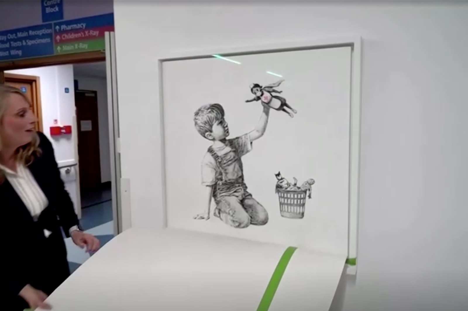 Chief executive of University Hospital Southampton NHS Foundation Trust, Paula Head, unveils Banksy's Game Changer artwork, in London, Britain March 16, 2021, in this still image taken from a video. (BBC/@banksy instagram/via Reuters)