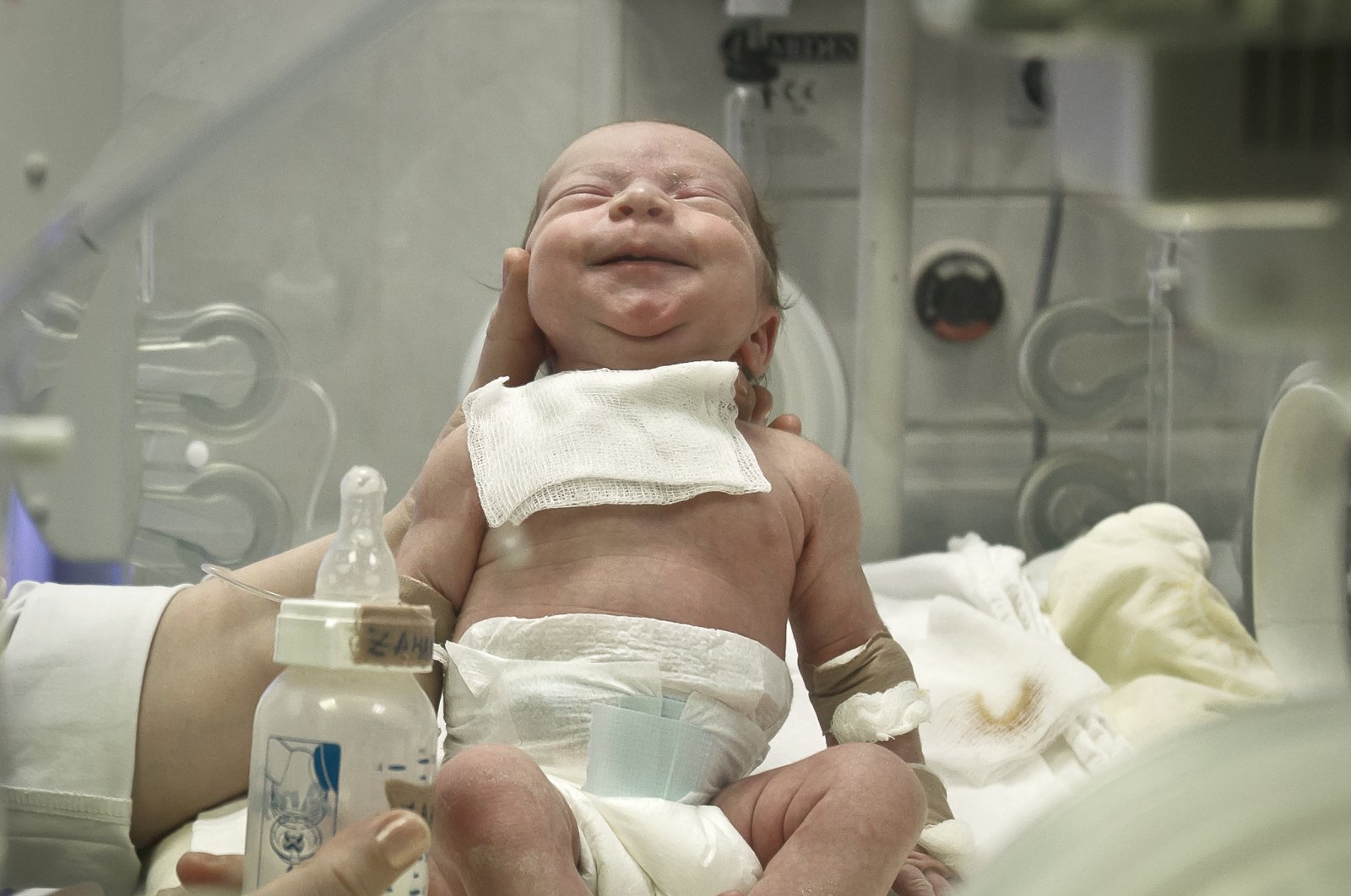 A newborn baby appears to smile after having a meal at the intensive care unit of the Marie Curie children's hospital, on March 18, 2012, in Bucharest, Romania. (AP File Photo)
