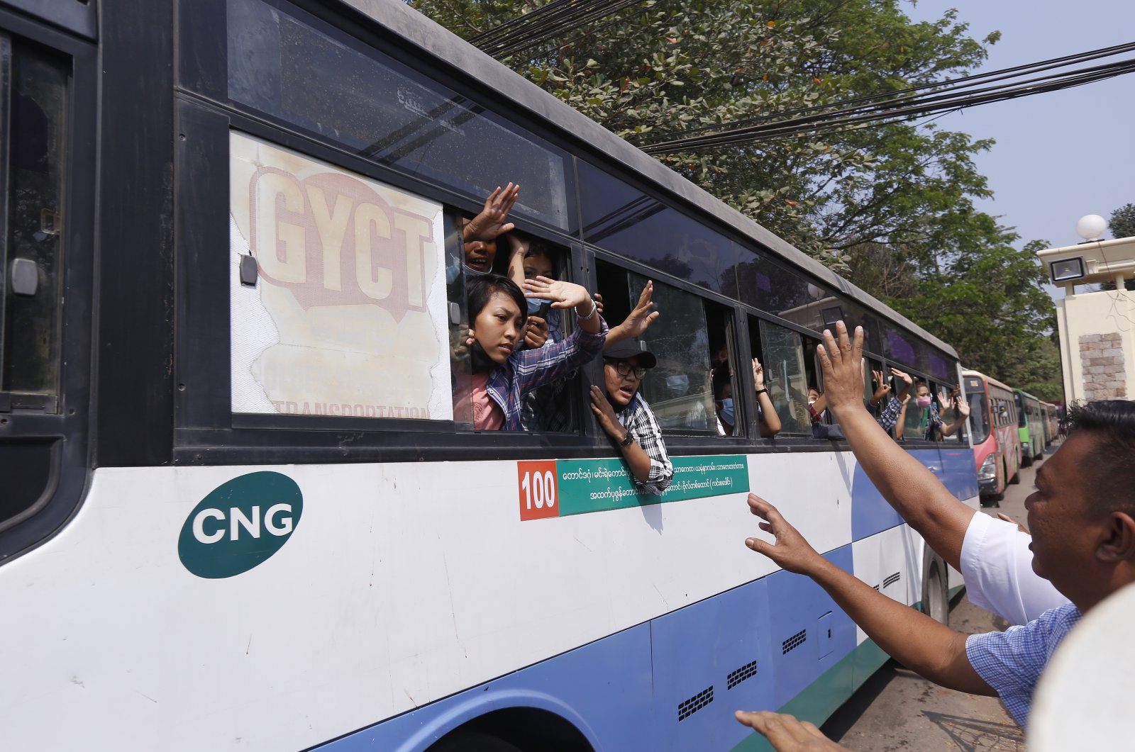 Arrested protesters wave to people while on board a bus that is part of a convoy of buses getting out of Insein prison and will transport them to an undisclosed location in Yangon, Myanmar, March 24, 2021. (AP Photo)