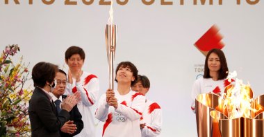 A member of Japan's women's national football team carries the torch during the Tokyo 2020 Olympic Torch Relay Grand Start in Naraha, Japan, March 25, 2021. (Reuters Photo)