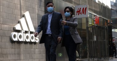 People walk by Adidas and H&M stores in Beijing, China, March 25, 2021. (AP Photo)