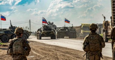 U.S. soldiers stand along a road across from Russian military armored personnel carriers (APCs), near the village of Tannuriyah in the countryside east of Qamishli in Syria's northeastern Hasakah province, May 2, 2020. (AFP Photo)