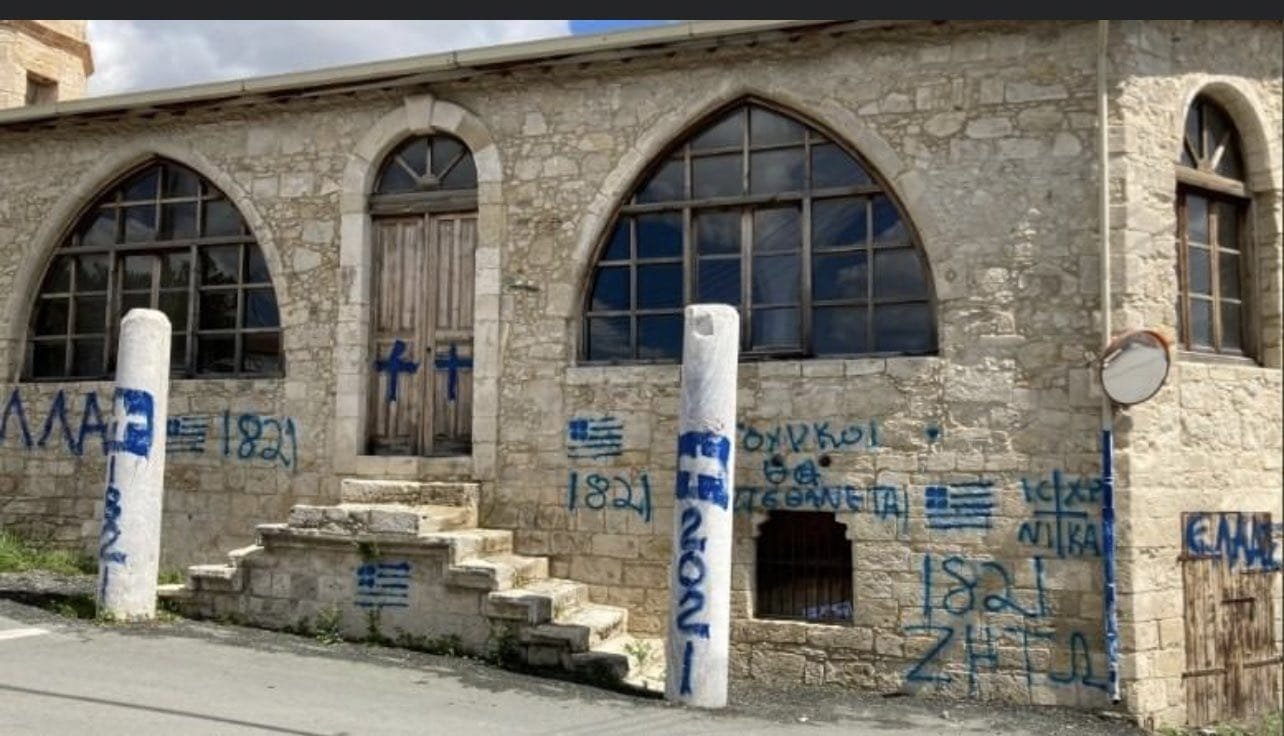 A mosque after it was vandalized by unidentified individuals who wrote slogans praising the Greek uprising on its anniversary of March 25, 1821, along with the Greek flag and a cross drawn on the walls and doors, in the village of Episkopi (Piskobu-Yalova) in Limassol, in the Greek Cypriot administration, March 25, 2021. (DHA Photo)