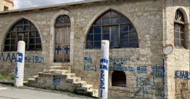 A mosque after it was vandalized by unidentified individuals who wrote slogans praising the Greek uprising on its anniversary of March 25, 1821, along with the Greek flag and a cross drawn on the walls and doors, in the village of Episkopi (Piskobu-Yalova) in Limassol, in the Greek Cypriot administration, March 25, 2021. (DHA Photo)