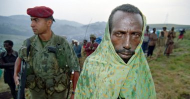 A Tutsi refugee waits in the rain near a French paratrooper at Nyarushishi refugee camp, Zaire border in Gisenyi, Rwanda, June 29, 1994. (AFP Photo)