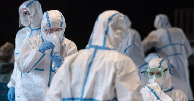 Employees at a Coronavirus testing center wear protective suits to protect themselves from infection with the virus, in Mainz, Germany, Friday March 26, 2021. (Boris Roessler/dpa via AP)