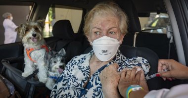A woman gets a shot of the Sinovac COVID-19 vaccine while she sits in her car with her pets during a priority vaccination program for seniors at a drive-thru site set up in the Pacaembu soccer stadium parking lot in Sao Paulo, Brazil,  March 3, 2021. (AP Photo)