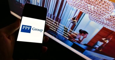 A view of a person holding a smartphone with the logo of financial and investment company PPF Group N.V. on display. (Shutterstock Photo)