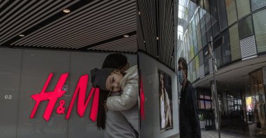 A woman with a child walks past an H&M store in a shopping area of Sanlitun, in Beijing, China, March 27, 2021. (EPA Photo)