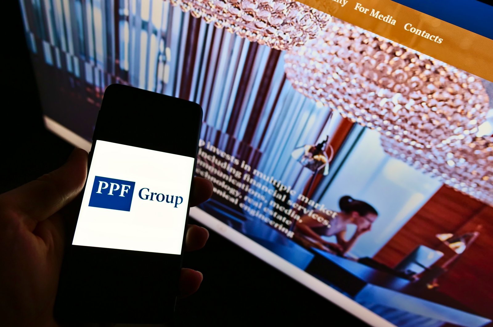 A view of a person holding a smartphone with the logo of financial and investment company PPF Group N.V. on display. (Shutterstock Photo)