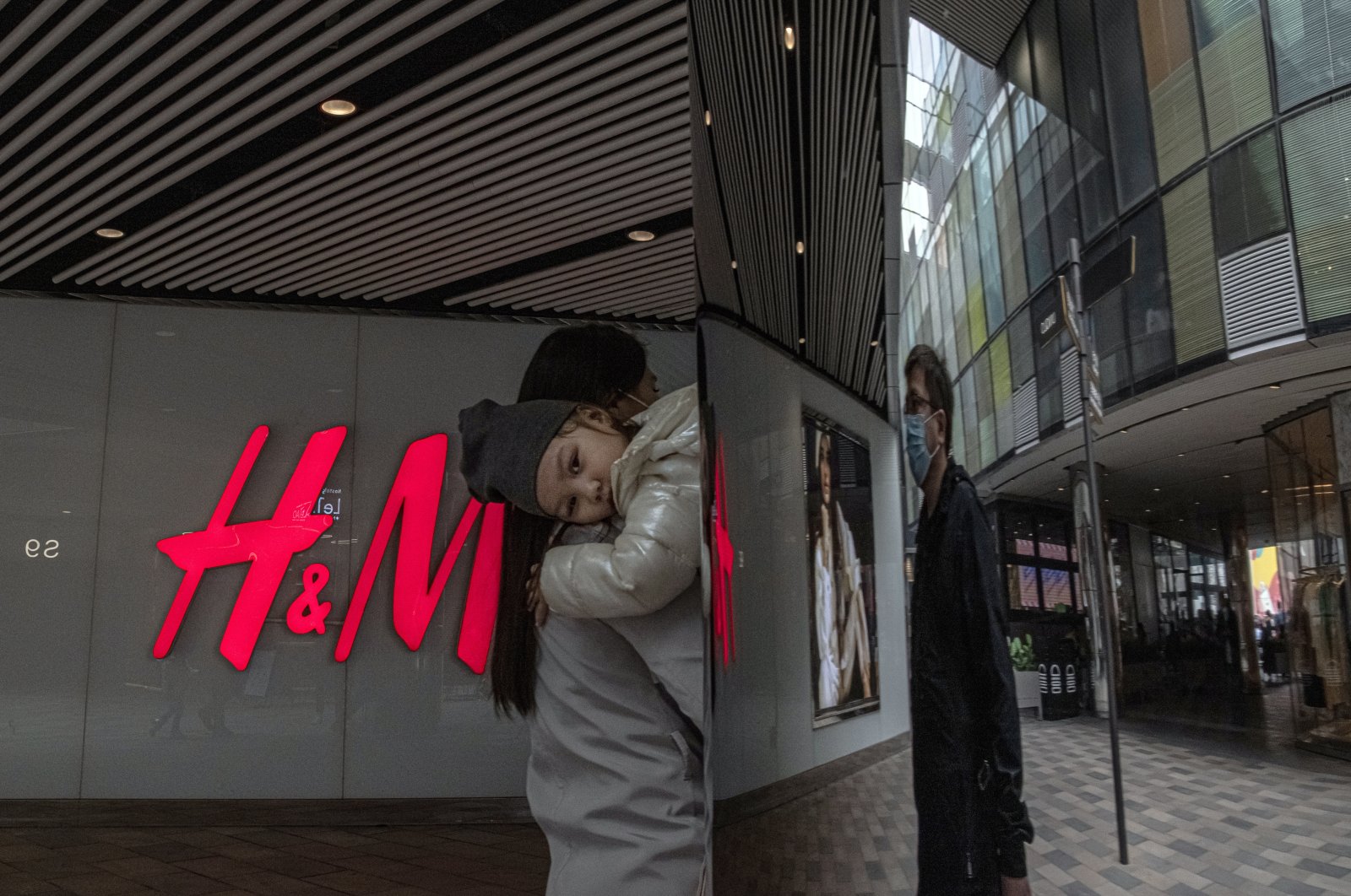 Eine Frau mit einem Kind geht am 27. März 2021 in einem Einkaufsviertel von Sanlitun in Peking, China, an einem H&M-Geschäft vorbei. (EPA-Foto)