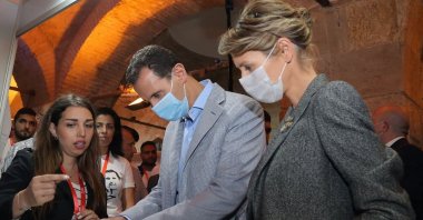 Syrian regime leader Bashar Assad (C) and wife Asma (R), wearing face masks due to the COVID-19 pandemic, attend a state-sponsored fair in Damascus, northern Syria, Nov. 4, 2020. (Syrian Arab News Agency via AFP)