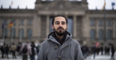 Tareq Alaows, who was running to become a lawmaker at the German parliament Bundestag but withdrew his candidacy, poses in front of the Reichstag building in Berlin, Germany, Feb. 6, 2021. (AP Photo)
